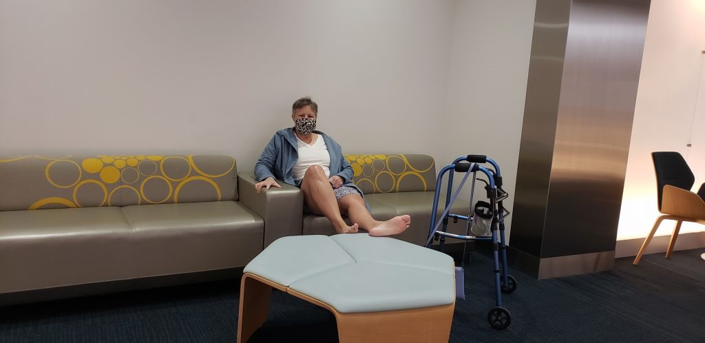 Kim sitting on couch in waiting room with leg on ottoman