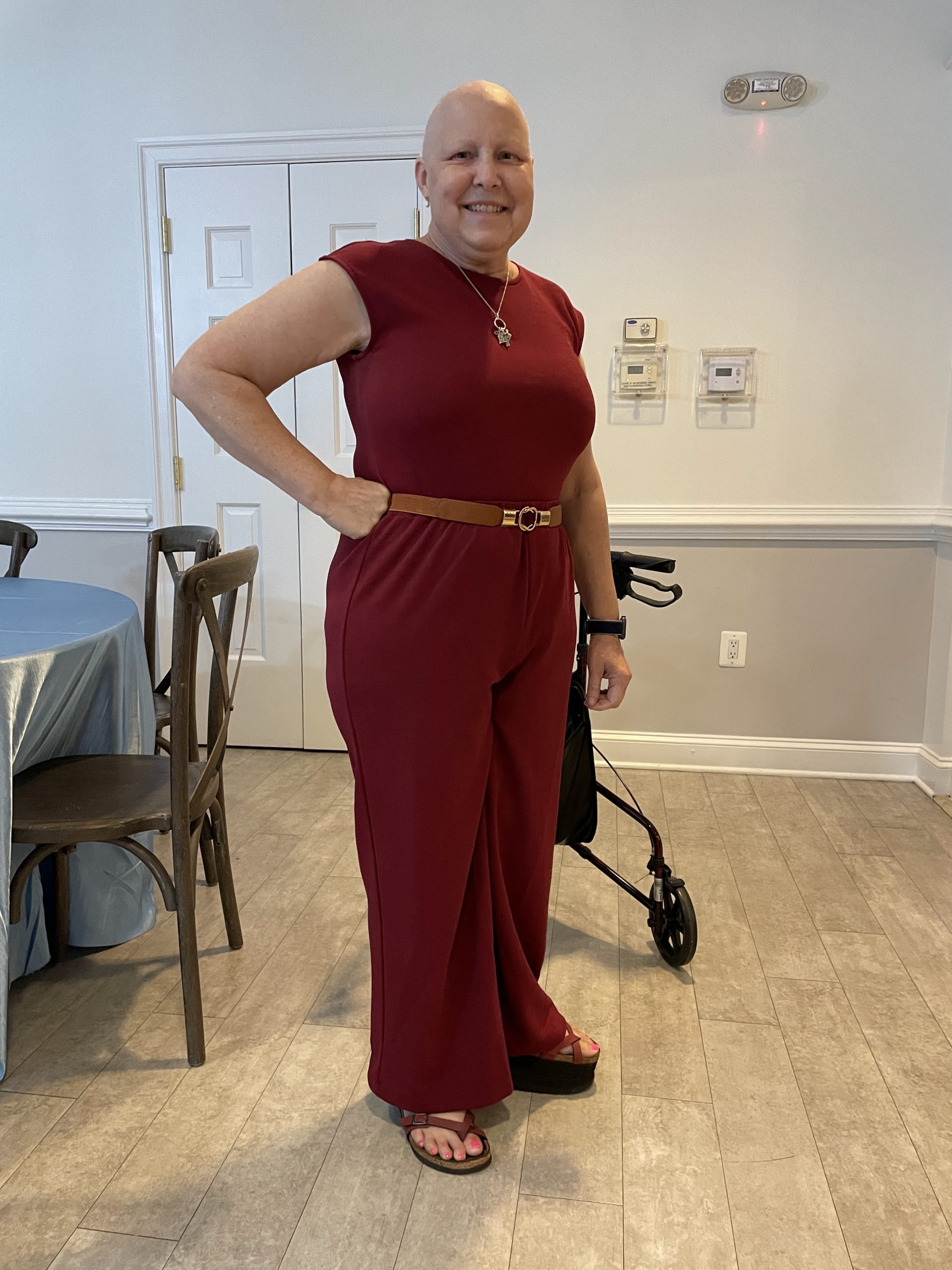 Kim wearing a maroon jumpsuit while attending her niece's wedding. Walker in background.